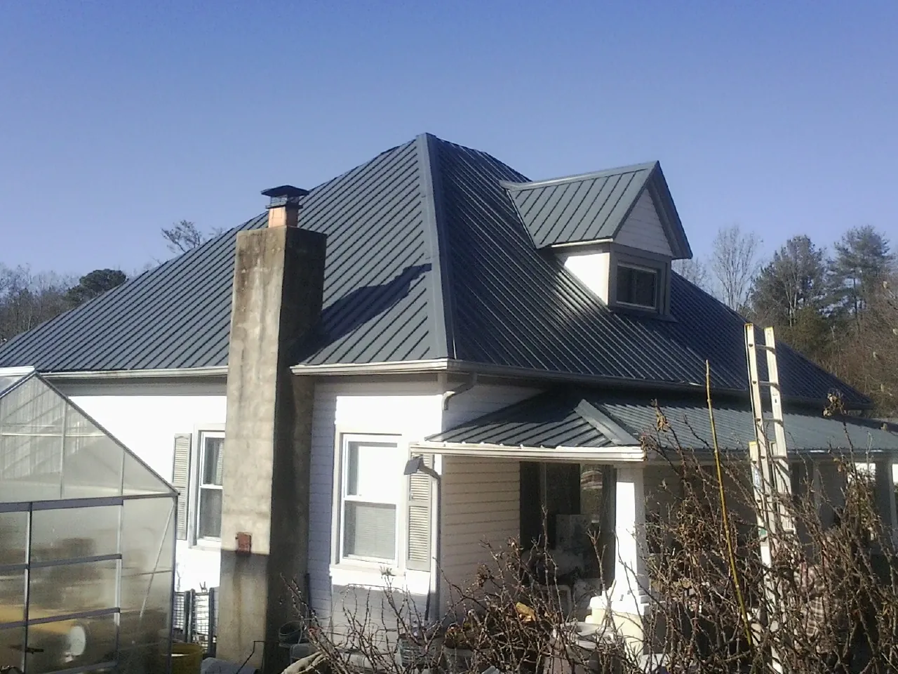 Dark blue standing seam metal roof on a white farmhouse with dormer — Slate & Tile Roof Repair by Roofing Brothers in Sadsburyville