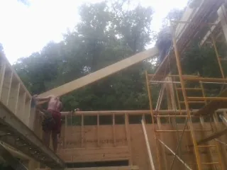 Carpenter raising a rafter beam on a new second story frame in Sadsburyville