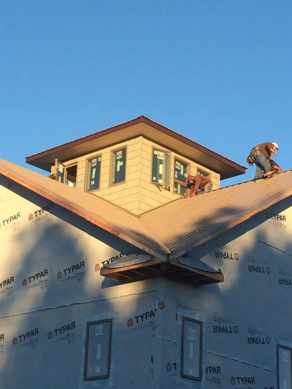 Roofers working around a rooftop cupola on a new metal roof at sunset — Roof Waterproofing in Sadsburyville by Roofing Brothers